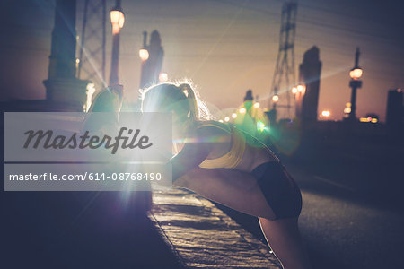 Young woman exercising outdoors, stretching