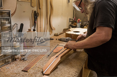 Guitar maker in workshop manufacturing guitar