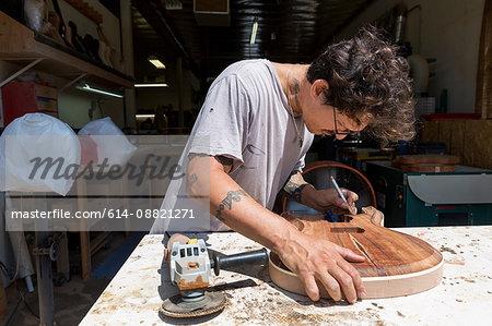 Guitar maker manufacturing guitar in workshop