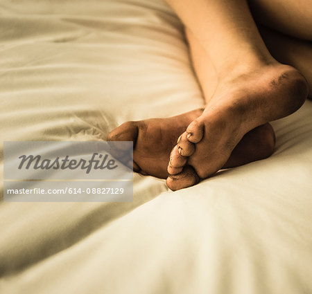 Cropped view of boys dirty bare feet on bed