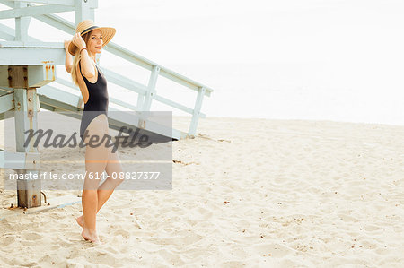 Woman wearing swimsuit by lifeguard tower looking away
