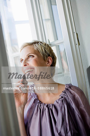 Woman talking on cell phone by window