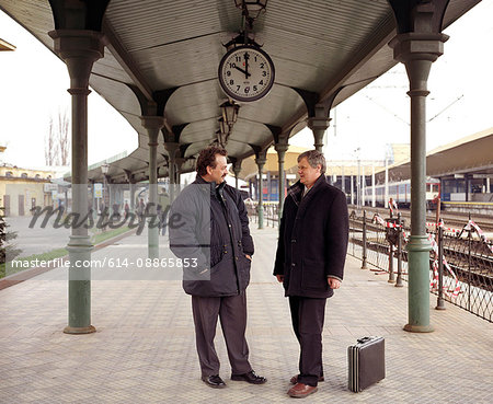 Two men talking on train platform