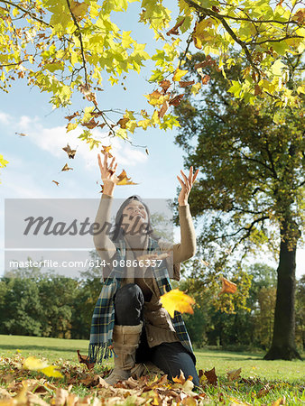Woman throwing Autumn leaves into air