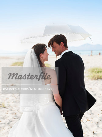 bride and groom walking under parasol