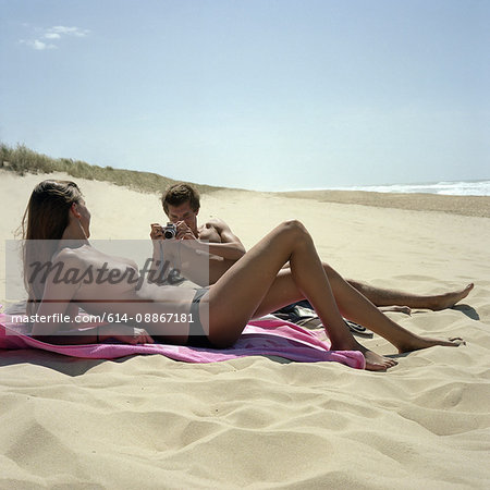 Guy photographing girl on beach