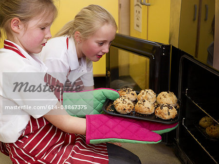 girls taking bread out of the oven