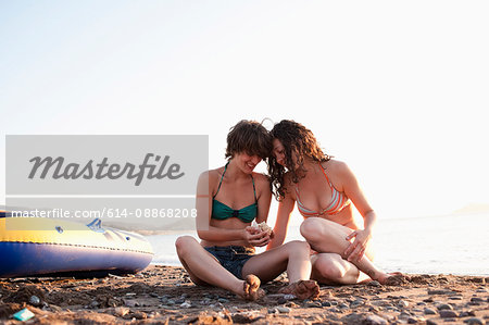 Women admiring seashells on beach