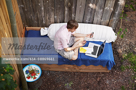 Man using laptop on sofa outdoors