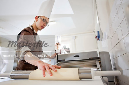 Baker rolling dough in kitchen