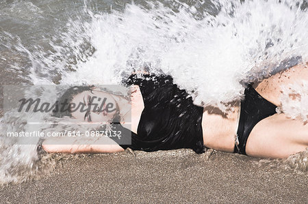 Woman laying in waves on beach