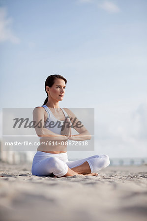 Woman practising yoga on a beach