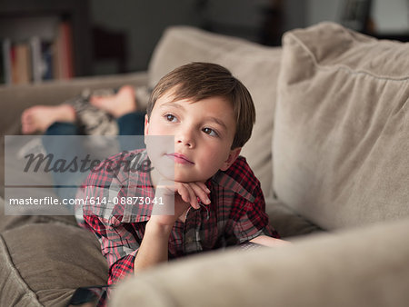 Boy lying on sofa, looking away
