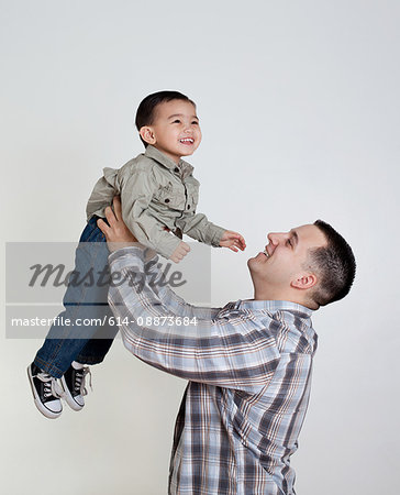 Young man holding son in the air, studio shot