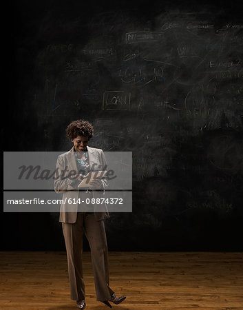 Woman by blackboard using digital tablet