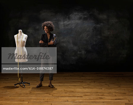 Businesswoman by blackboard with tailors dummy