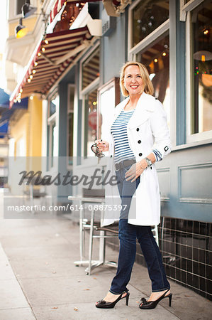 Mature woman in white coat and jeans, smiling