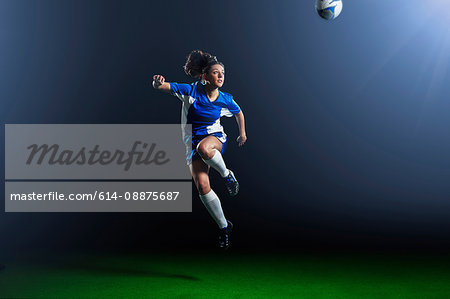 Young female soccer player mid air