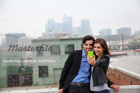 Couple making self portrait on city rooftop