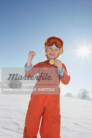 Young boy showing off medal around neck, low angle view