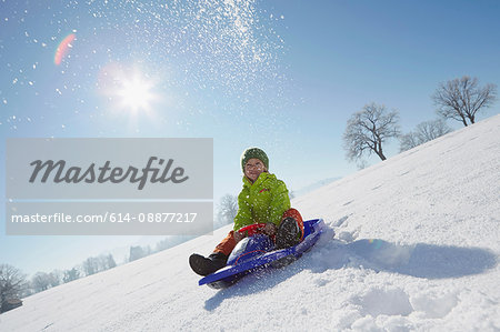 Young boy sitting on sled in snowy landscape