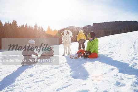 Children and pet dog enjoying playing in snow