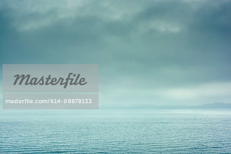 View of horizon over calm water with dramatic stormy sky