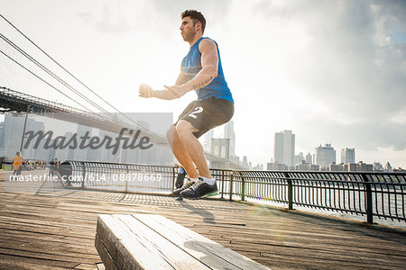 Young man doing jump training on riverside, Brooklyn, New York, USA