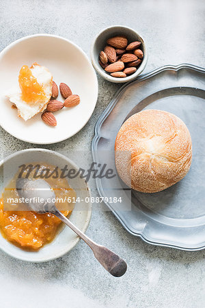 Overhead view of bread rolls with marmalade and bowl of nuts