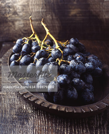 Bunch of black grapes in vintage wooden bowl
