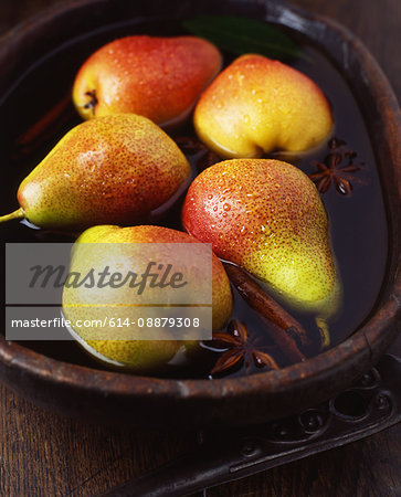 Seckel pears with cinnamon stick and star anise in vintage wooden bowl of water