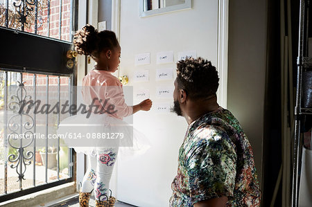 Girl in tutu with father reading words on wall