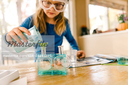 Girl doing science experiment, pouring liquid into flask