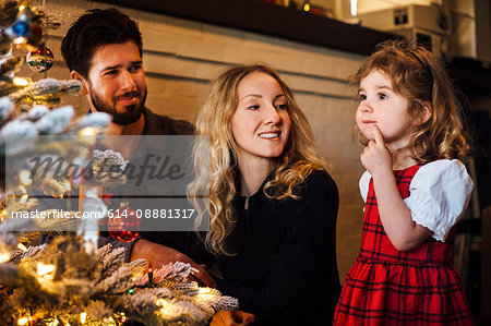 Female toddler with parents gazing at christmas tree