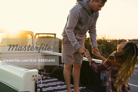 Couple holding hands at back of pickup truck at Newport Beach, California, USA