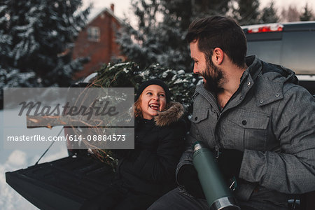 Father and daughter on back of pick up truck with their Christmas tree