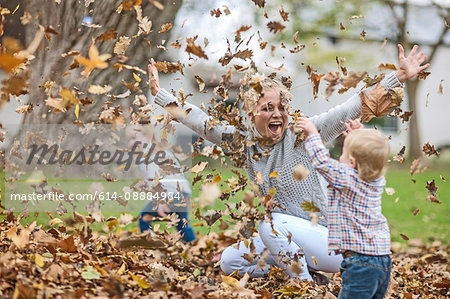 Mother and children playing with fallen leaves