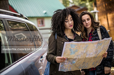 Two friends standing beside car, looking at map