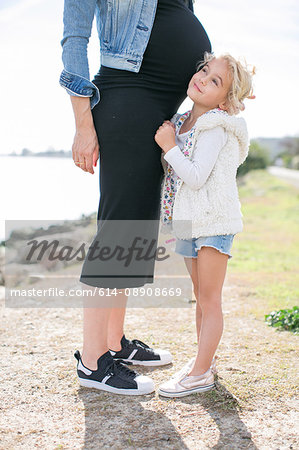 Cropped shot of pregnant mother and daughter at coast