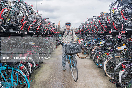 Cyclist on bicycle looking at camera giving thumbs up, Amsterdam, Netherlands