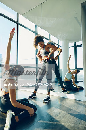 Two young women exercising in gym, stretching