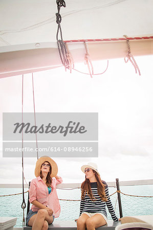 Two women on sitting on deck of sailing boat, on sea