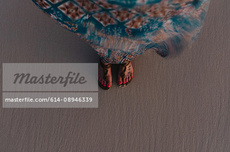 High angle view of woman's feet on sand