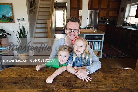 Portrait of father at kitchen table with daughter and son