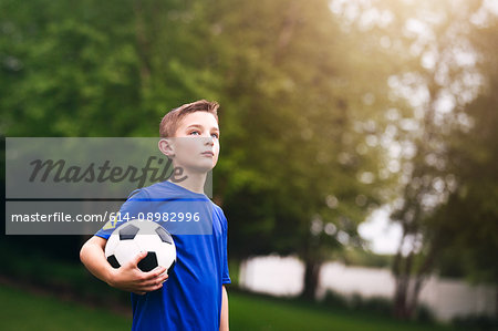 Boy holding soccer ball looking away