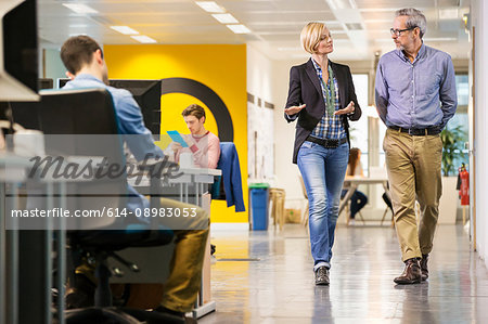 Female and male digital designers walking and talking in office