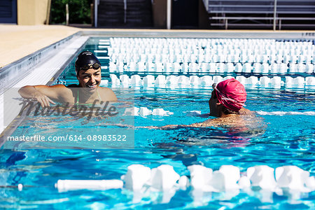 Swimmer in water at end of pool talking to friend