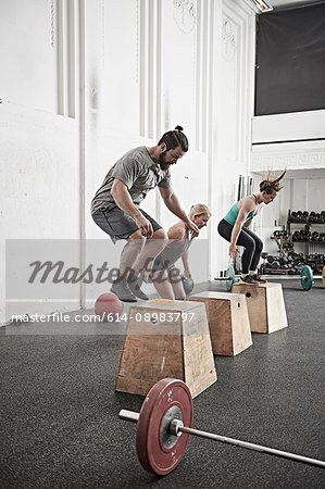 Friends jumping onto fitness box in cross training gym
