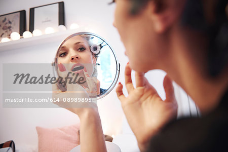 Mirror image of woman applying lipstick