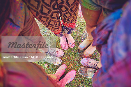 Overhead view of young adults in circle covered in coloured chalk powder at festival